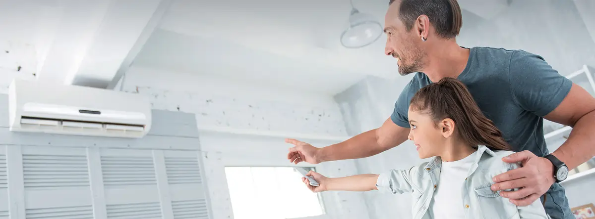 Father and daughter controlling their heat pump with a remote